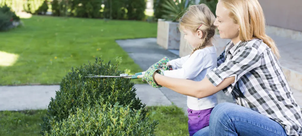 mother and child trimming hedges
